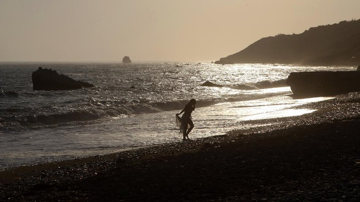 People enjoy the sea at Aphrodite's Rock, 'Petra tou Romiou', the spot where according to ancient Greek mythology the ancient goddess Aphrodite was born, near Paphos, Cyprus, Monday, July 13, 2020. (AP Photo/Petros Karadjias)