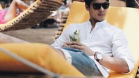 Berbeda dengan posenya yang ini. Ia memilih untuk memegangi segelas minuman segar itu sambil berbaring lengkap dengan sunglasses. Foto: Instagram @rizkybillar
