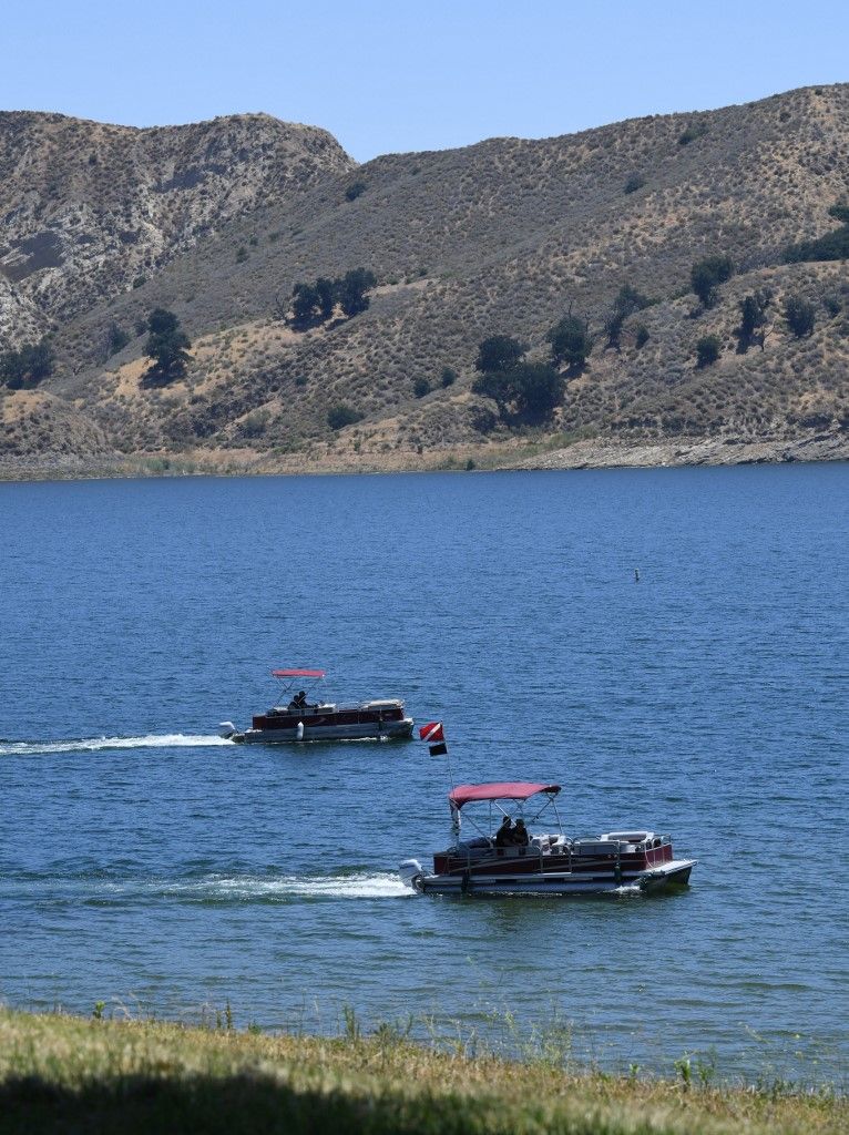 Ventura County Sheriff's deputies stand near a vehicle near the shoreline at Lake Piru, north of Los Angeles, California, on July 13, 2020, where a body presumed to be missing 