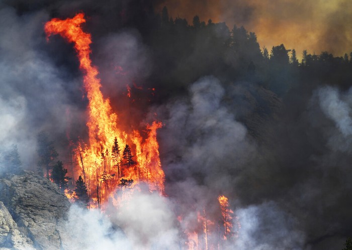 Colorado Wildfires A wildfire burns Monday, July 13, 2020, near Evergreen, Colo. Cooler temperatures and light rain have combined on Tuesday, July 14, to give firefighters hope that they can contain the fire, which has yet to cause any injuries or consume any structures but has forced the evacuation of 1,000 residents of the scenic area. (RJ Sangosti/The Denver Post via AP)/The Denver Post via AP)