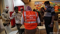 Warga yang kedapatan melanggar wajib mengenakan rompi oranye bertuliskan Pelanggar.