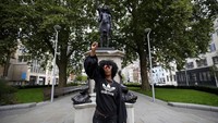 Jen Reid berfoto di depan patung dirinya yang berjudul  A Surge of Power (Jen Reid) 2020 karya seniman Marc Quinn di kawasan Bristol, Inggris, Rabu (15/7/2020). AP Photo/Matt Dunham.