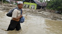 Warga berusaha menerobos banjir di Desa Radda, Kabupaten Luwu Utara, Sulawesi Selatan, Selasa (14/7/2020). ANTARA FOTO/Hariandi Hafid.