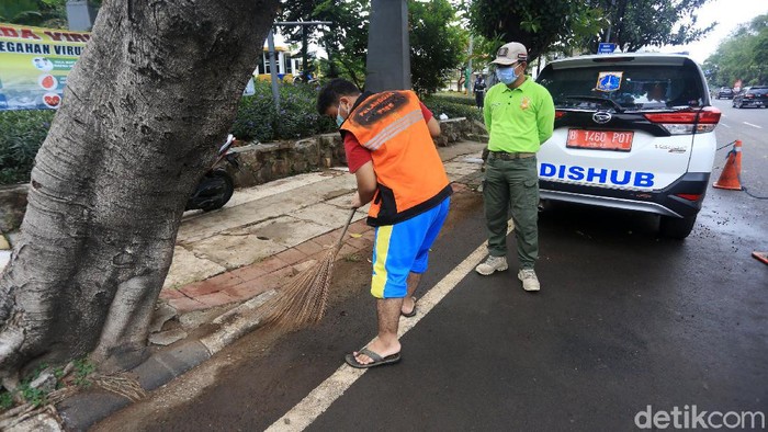 Pelanggar aturan pembatasan sosial berskala besar (PSBB) melaksanakan sanksi kerja sosial dengan menyapu sampah di Jalan Basuki Rahmat, Jakarta Timur, Rabu (15/7/2020).