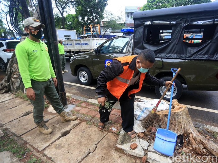 Pelanggar aturan pembatasan sosial berskala besar (PSBB) melaksanakan sanksi kerja sosial dengan menyapu sampah di Jalan Basuki Rahmat, Jakarta Timur, Rabu (15/7/2020).