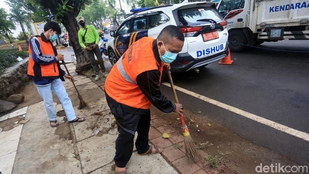 Pelanggar aturan pembatasan sosial berskala besar (PSBB) melaksanakan sanksi kerja sosial dengan menyapu sampah di Jalan Basuki Rahmat, Jakarta Timur, Rabu (15/7/2020).
