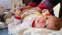 Di Aleppo Timur, seorang bayi bersuai tiga bulan bernama Zuka menerima vaksin di dalam klinik. WHO terus mengupayakan kampanye imunisasi nasional di seluruh Suriah. Kampanye tersebut menjangkau 900.000 anak dengan petugas medis yang dikerahkan sebanyak 8.000 lebih. Tak hanya itu, 1.000 pusat kesehatan, 666 pos vaksinasi dan 545 tim medis terus berupaya keras.