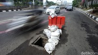 Selain dipasangi tanaman, jalan berlubang di bagian lainnya juga tampak dipasangi barrier sebagai penanda bagi para pengguna jalan yang melintas di kawasan tersebut.