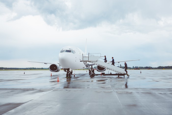 Business people boarding airplane, walking up the staircase.