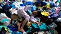 Anak-anak tidur dengan beralaskan tumpukan pakaian bekas layak pakai yang disumbangkan oleh warga.
