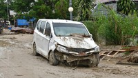 Banjir yang terjadi pada Senin (13/7) lalu turut membawa lumpur dan material kayu hingga pohon. Tampak mobil warga rusak parah akibat banjir. (dok. Istimewa).