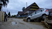 Sebuah mobil terseret banjir bersama batang-batang pohon.