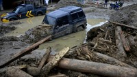 Sepertinya dua mobil ini akan sulit keluar dari kubangan sisa banjir.