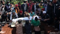 Sang anak, Dio Ambya, turun ke liang lahat untuk menguburkan Omas. Pool/Palevi S/detikFoto.