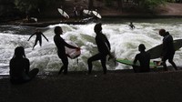 Para peselancar beraksi di kanal Eisbach, Munich, Jerman, Kamis, 16 Juli 2020 waktu setempat.