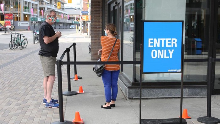 A sporting goods store clerk (L) explains shopping rule to a customer May 19, 2020 in Ottawa, Canada. - Ontario, Canadas most populous province, is allowing stores with street access to reopen, along with hospital surgery rooms, dog parks and golf courses. (Photo by Dave Chan / AFP)