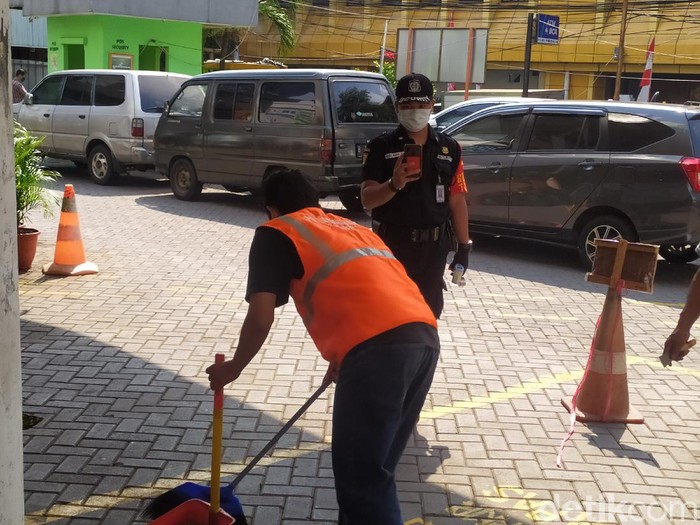 Karena tidak menggunakan masker, salah seorang warga dikenakan sanksi sosial menyapu halaman Pasar Gondangdia, Jakarta Pusat.