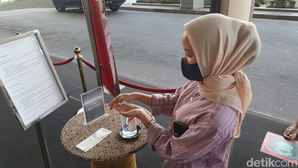 Setelah pemeriksaan suhu tubuh, kamu juga harus membersihkan tangan dengan hand sanitizer yang tersedia di bagian pemeriksaan. Terlihat petugas keamanan dan para staff hotel mengenakan masker dan face shield. (Syanti/detikcom) Setelah pemeriksaan suhu tubuh, kamu juga harus membersihkan tangan dengan hand sanitizer yang tersedia di bagian pemeriksaan. Terlihat petugas keamanan dan para staff hotel mengenakan masker dan face shield. (Syanti/detikcom)
