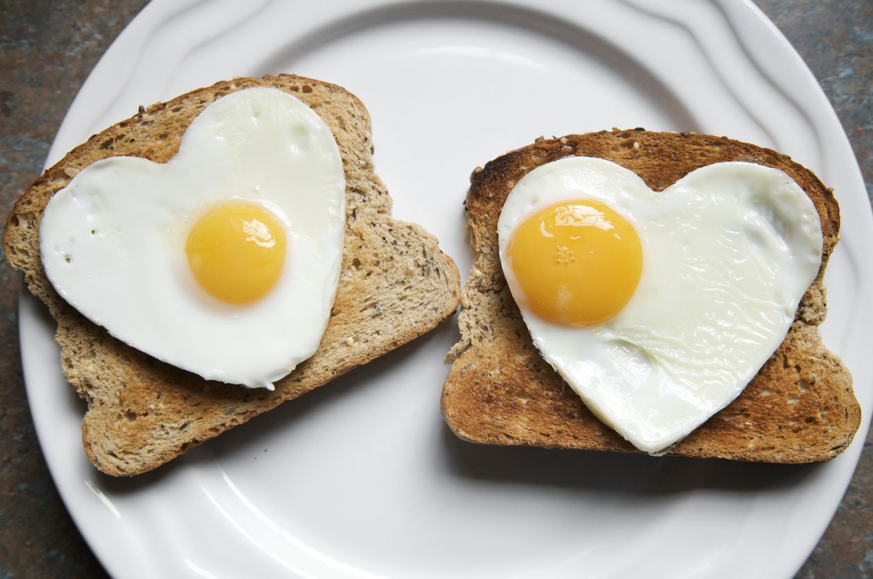 Pair of fried eggs in the shape of hearts on two pieces of toast on a plate