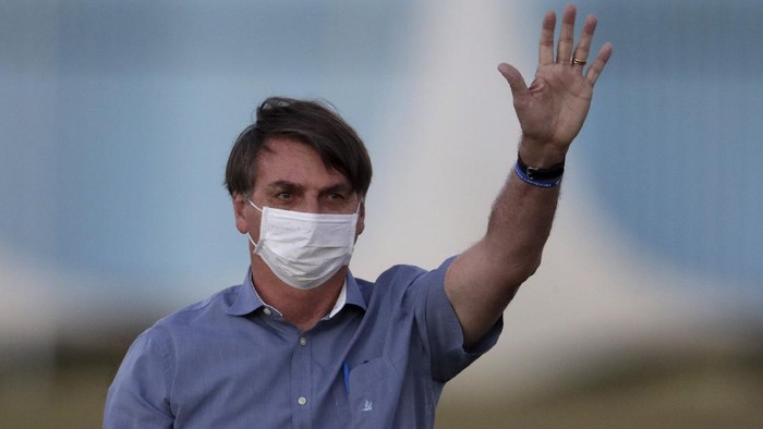 Brazils President Jair Bolsonaro who is infected with COVID-19, wears a protective face mask as he waves to supporters during a Brazilian flag retreat ceremony outside his official residence Alvorada Palace, in Brasilia, Brazil, Friday, July 17, 2020. On Thursday evening, the federal health ministry reported that the country had passed 2 million confirmed cases of virus infections and 76,000 deaths. (AP Photo/Eraldo Peres)