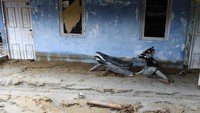 Sebuah motor terendam sisa lumpur setinggi kurang lebih setengah meter yang terparkir di depan rumah warga yang diterjang banjir bandang tersebut.