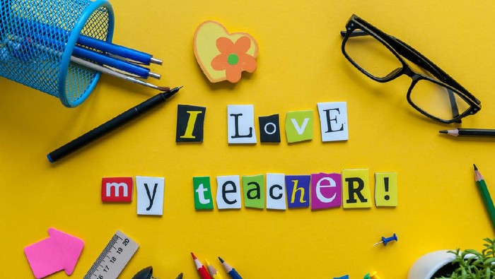 i love my Teacher - text made with carved letters on yellow desk with office or school supplies on pupil table.