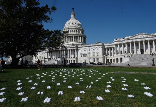 Pada Selasa (21/7/2020), para perawat menaruh 164 pasang sepatu putih di halaman depan Gedung Parlemen Amerika Serikat, Washington, D.C. Foto: AFP/OLIVIER DOULIERY