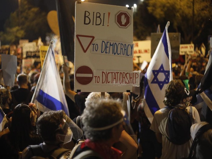 Demonstrators hold signs during a protest against Israels Prime Minister Benjamin Netanyahu in front of the Knesset, Israels parliament in Jerusalem, Tuesday, July 21, 2020. Thousands of Israelis marched back to Netanyahus official residence after protesting outside the Knesset, the countrys parliament. (AP Photo/Ariel Schalit)