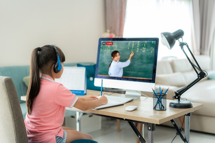 Asian  student girl video conference e-learning with teacher on computer in living room at home. E-learning ,online ,education and internet social distancing protect from COVID-19 virus.