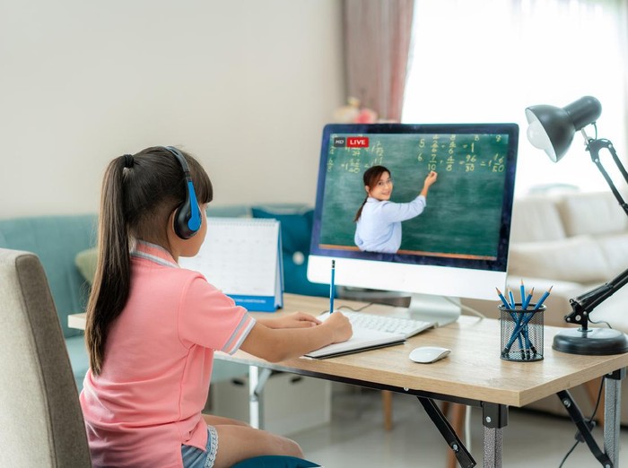 Asian  student girl video conference e-learning with teacher on computer in living room at home. E-learning ,online ,education and internet social distancing protect from COVID-19 virus.