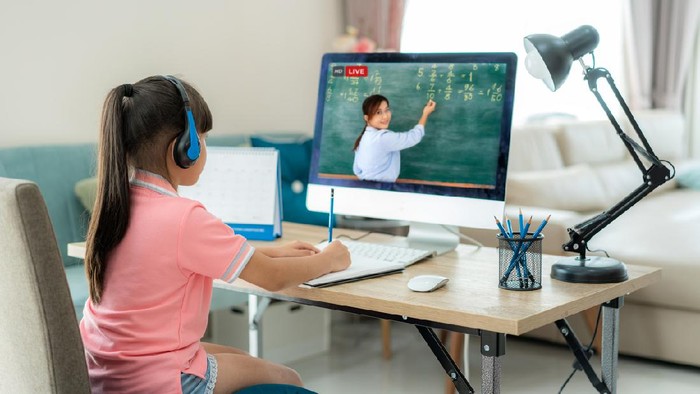 Asian  student girl video conference e-learning with teacher on computer in living room at home. E-learning ,online ,education and internet social distancing protect from COVID-19 virus.