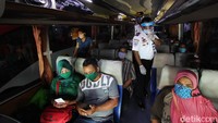Petugas masuk ke dalam bus untuk memastikan semua penumpang mengenakan masker.