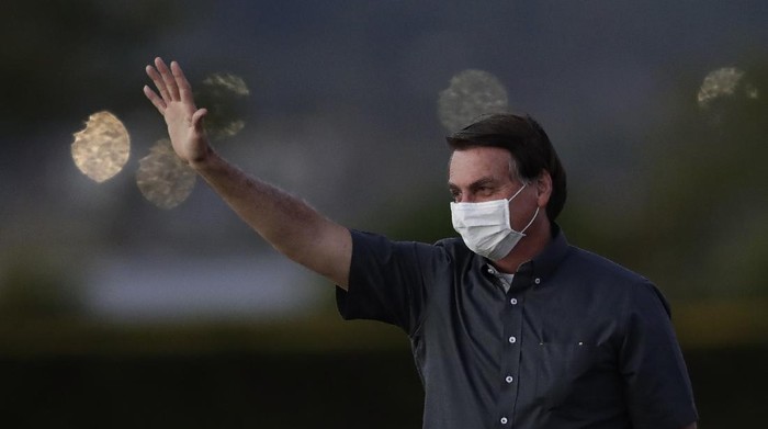 Brazils President Jair Bolsonaro who is infected with COVID-19, wears a protective face mask as he waves to supporters during a Brazilian flag retreat ceremony outside his official residence the Alvorada Palace, in Brasilia, Brazil, Monday, July 20, 2020. (AP Photo/Eraldo Peres)