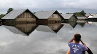 Warga menggunakan rakit melintasi rumah yang terendam banjir di Desa Laloika, Kecamatan Pondidaha, Kabupaten Konawe, Sulawesi Tenggara, Rabu (22/7/2020). 