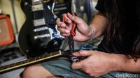Ridwan tengah teliti memperbaiki gitar yang rusak.