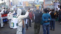 Petugas menyemprotkan cairan disinfektan ke warga yang tergabung dalam Aliansi Masyarakat Jember (AMJ) saat melakukan aksi di bundaran DPRD Jember, Jawa Timur, Rabu (22/7/2020).