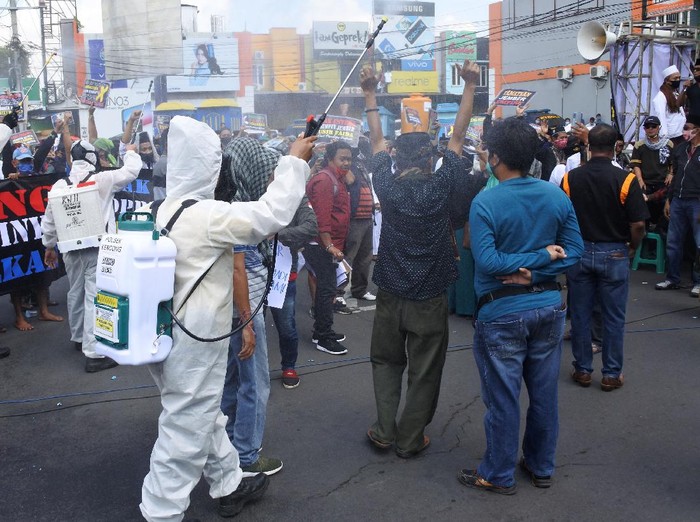 Sejumlah warga gelar aksi unjuk rasa di bundaran DPRD Jember, Jatim. Di tengah aksi, sejumlah petugas semprotkan cairan disinfektan kepada para demonstran.