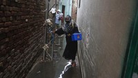 Seorang petugas kesehatan berjalan melalui jalan sempit yang dipenuhi air limbah ketika dia mendekati sebuah rumah untuk memberikan vaksinasi polio, di Lahore, Pakistan. AP Photo/K.M. Chaudary  