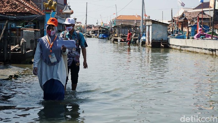 Petugas Pemutakhiran Data Pemilih (PPDP) KPU harus jalan kaki menerobos banjir rob di di Desa Purworejo, Demak, Selasa (21/7/2020). Akibatnya, target Coklit yang dilakukannya tidak bisa sesuai target ideal harian.