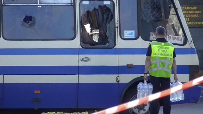 A policeman brings water for hostages contained in a bus after an armed man seized the long-distance bus and took some 10 people hostage in the city centre of Lutsk, some 400 kilometers (250 miles) west of Kyiv, Ukraine on Tuesday July 21, 2020. The assailant is armed and carrying explosives, according to a Facebook statement by Ukrainian police. Police officers are trying to get in touch with the man and they have sealed off the area. (Ukrainian Police Press Office via AP)