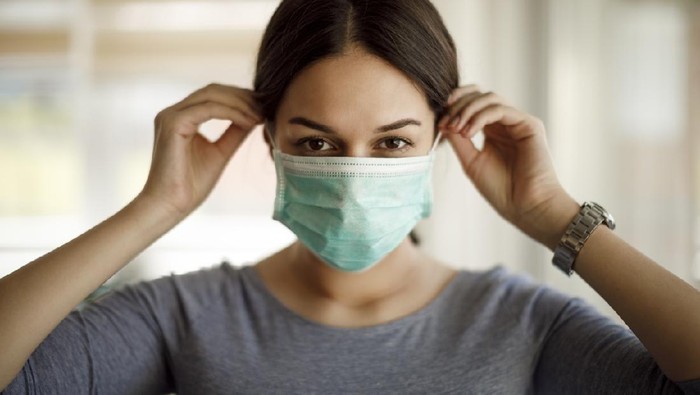 Portrait of young woman putting on a protective mask