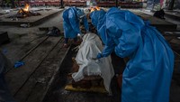 Proses kremasi mengedepankan protokol kesehatan. Dua petugas mengenakan APD lengkap dengan face shield dan masker.
