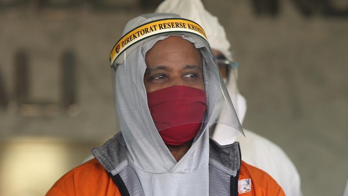 U.S. national Marcus Beam, center, wearing protective equipment as precaution against the coronavirus, is flanked by police as he is presented to the media during a press conference at the Regional Police Headquarters in Denpasar, Bali, Indonesia, Friday, July 24, 2020. Authorities on the resort island arrested Beam, an American fugitive accused of investment fraud in the United States involving hundreds of thousands of dollars, police said Friday. The U.S. Securities and Exchange Commission said on its website that Beam, of Woodridge, Illinois, is accused of misappropriating about $500,000 from investors that was supposed to be placed in investment funds. (AP Photo/Firdia Lisnawati)