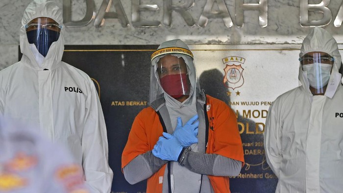 U.S. national Marcus Beam, center, wearing protective equipment as precaution against the coronavirus, is flanked by police as he is presented to the media during a press conference at the Regional Police Headquarters in Denpasar, Bali, Indonesia, Friday, July 24, 2020. Authorities on the resort island arrested Beam, an American fugitive accused of investment fraud in the United States involving hundreds of thousands of dollars, police said Friday. The U.S. Securities and Exchange Commission said on its website that Beam, of Woodridge, Illinois, is accused of misappropriating about $500,000 from investors that was supposed to be placed in investment funds. (AP Photo/Firdia Lisnawati)