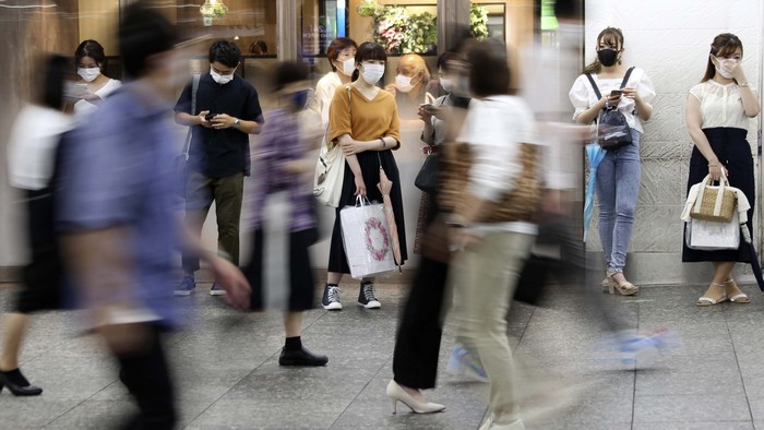 People wearing face masks to protect against the spread of the new coronavirus move at Yokohama station near Tokyo, Wednesday, July 22, 2020. (AP Photo/Koji Sasahara)