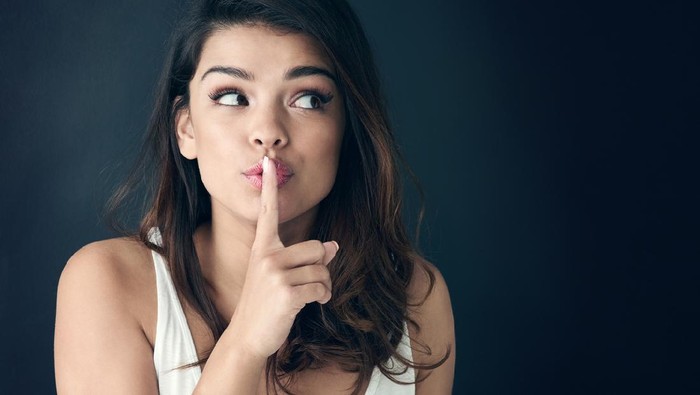 Studio shot of a beautiful young woman posing with her finger on her lips