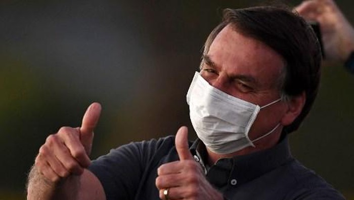 (FILES) In this file picture taken on July 20, 2020 Brazilian President Jair Bolsonaro gives the thumbs up to supporters from the Alvorada Palace in Brasilia, amid the new coronavirus pandemic. - Brazilian President Jair Bolsonaro announced on July 25, 2020 he has tested negative for the new coronavirus more than two weeks after being diagnosed on July 7, attributing his recovery to an unproven malaria drug. (Photo by EVARISTO SA / AFP)