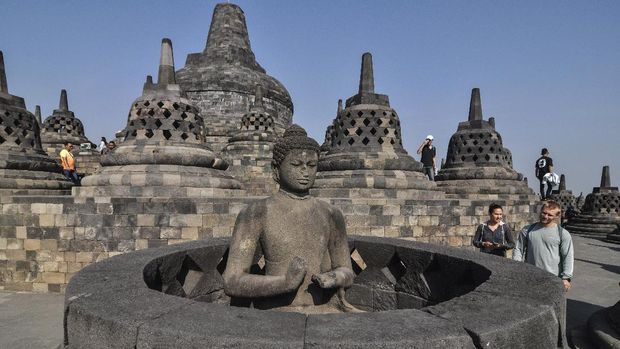 In this Monday, Aug. 12, 2019, photo, tourists inspect a Buddha statue at Borobudur Temple in Magelang, Central Java, Indonesia. The Indonesian city of Yogyakarta and its hinterland are packed with tourist attractions, including Buddhist and Hindu temples of World Heritage. Yet many tourists still bypass the congested city and head to the relaxing beaches of Bali. Recently re-elected President Joko Widodo wants to change this dynamic by pushing ahead with creating 