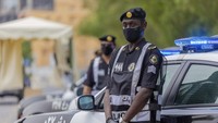 Polisi dengan memakai masker dan sarung tangan menjaga para jemaah yang baru datang. Saudi Ministry of Media via AP.