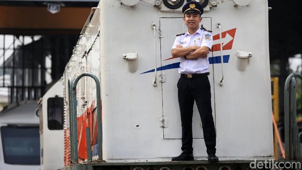 Seorang masinis berpose di depan lokomotif kereta.